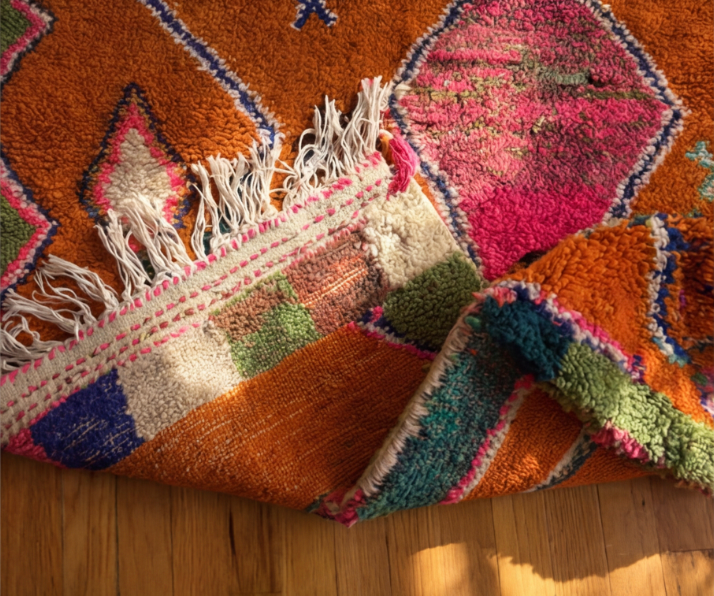 Noura rug close-up showing dense pile and scattered geometric motifs in pink, blue and white